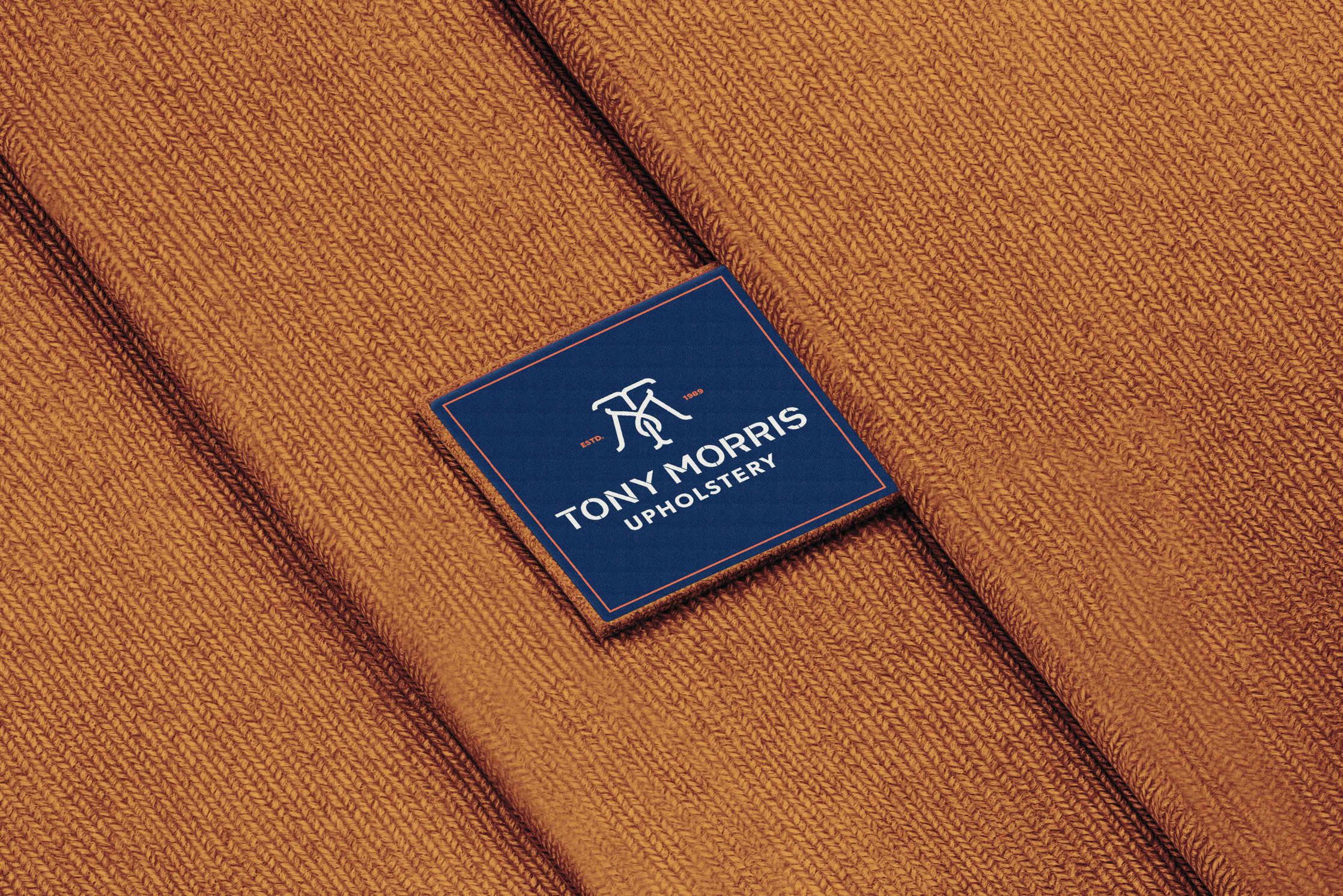 Woven Tony Morris label stitched onto orange fabric